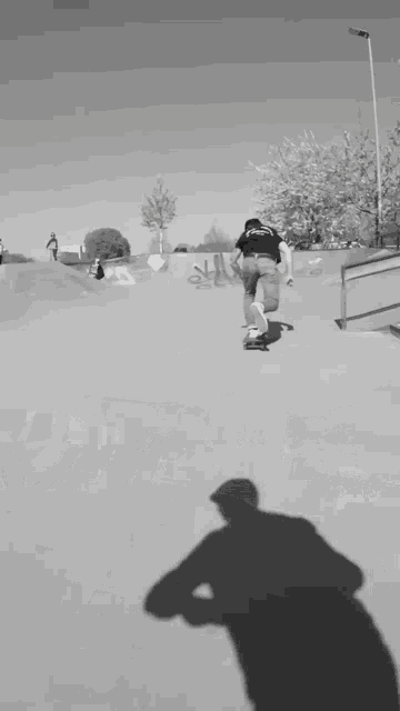 a man is riding a skateboard on a ramp with a skeleton on a motorcycle behind him