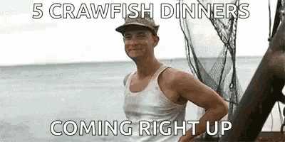 a man in a tank top is standing on a boat in the ocean with a fishing net in the background .