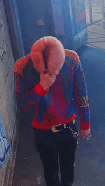 a young man with pink hair is wearing a colorful sweater and a bandana .