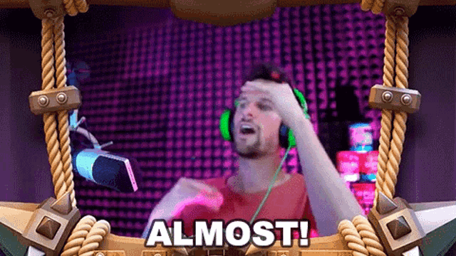a man wearing headphones and a red shirt is standing in front of a microphone with the word almost on the bottom