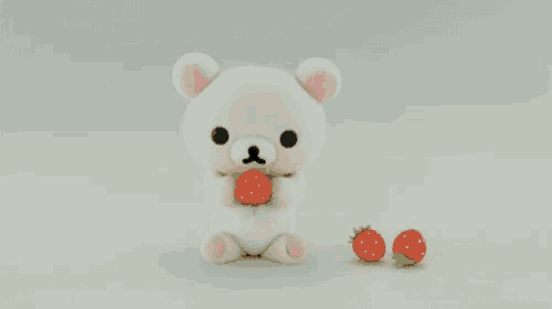 a white teddy bear holding a strawberry next to two small strawberries