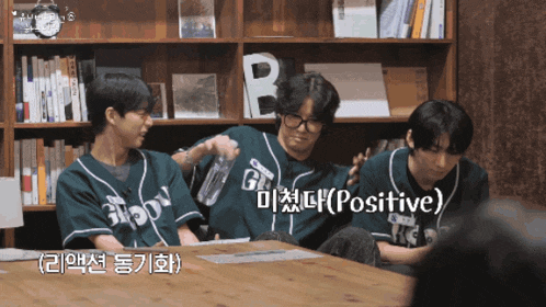 a group of young men are sitting around a table and one of them is wearing a green shirt that says ' positive ' on it