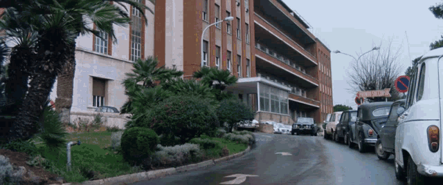 a row of cars are parked in front of a building with a sign that says " clinica universitaria "
