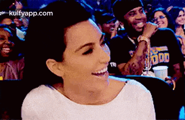 a woman is sitting in a crowd of people laughing and smiling .