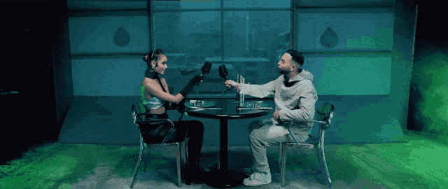 a man and a woman are sitting at a table and the man is holding a glass of wine