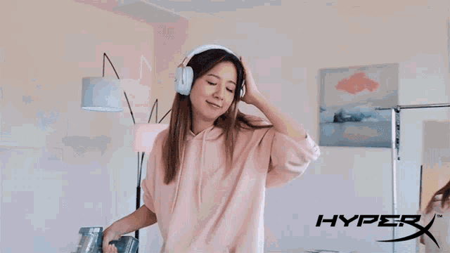 a woman wearing headphones is standing in front of a sign that says hyper x