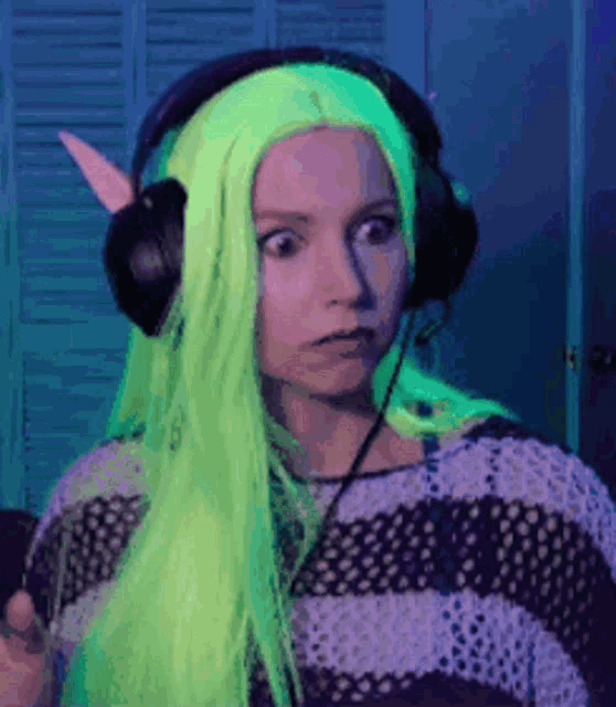 a woman with neon green hair is wearing headphones and a striped sweater .