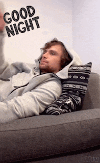 a man in a hoodie is laying on a couch with the words good night written on the wall behind him