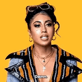 a woman wearing sunglasses , a necklace , and a jacket is saying `` damn '' .