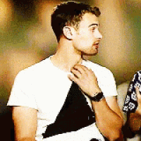 a man wearing a white t-shirt and a black and white triangle shirt is adjusting his tie .