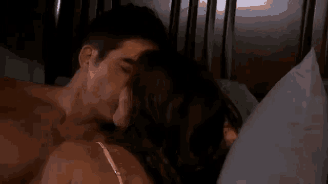 a man and a woman are laying in bed , the woman is holding the man 's arm .