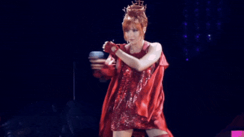 a woman in a red dress is holding a microphone in her hand