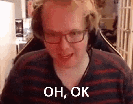 a man wearing glasses and a striped shirt is sitting in a chair and making a funny face .