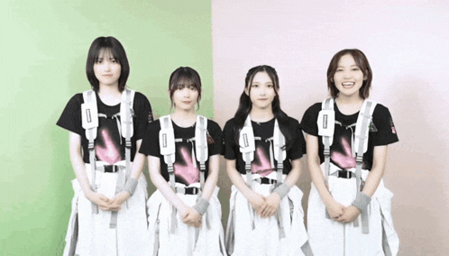 a group of girls are standing next to each other in front of a pink and green wall .