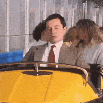 a man in a suit and tie is sitting in a yellow vehicle
