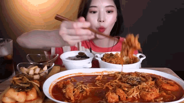 a woman with chopsticks is eating a large plate of food