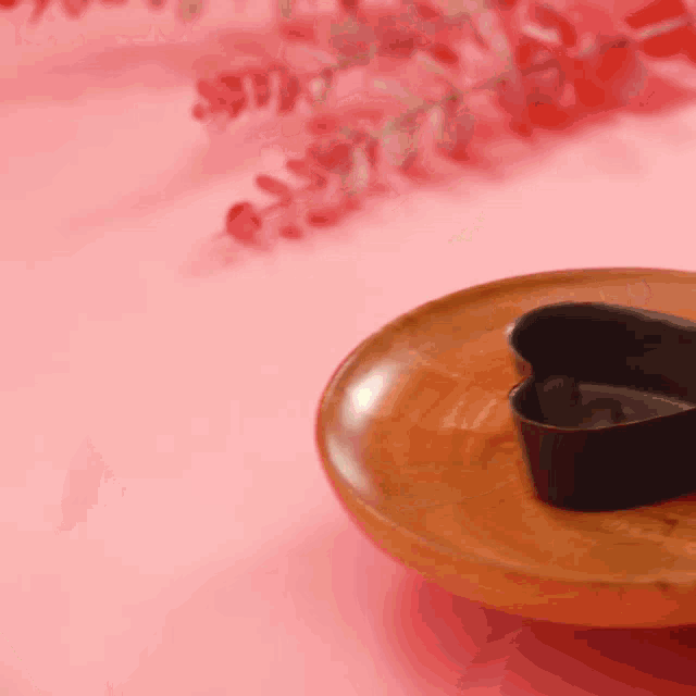 a heart shaped cookie cutter is sitting on a wooden plate