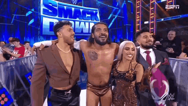 a group of wrestlers are posing for a picture together in front of a smack down sign .
