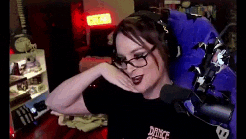 a woman wearing glasses and headphones is sitting in front of a microphone in a purple chair .