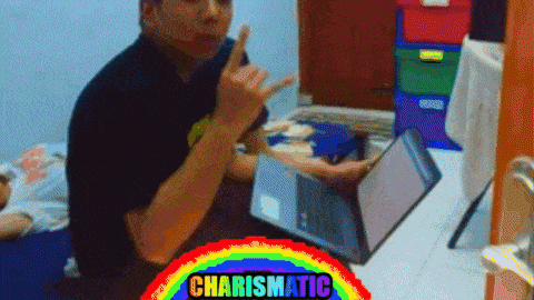 a man is sitting in front of a laptop with a rainbow behind him that says charismatic