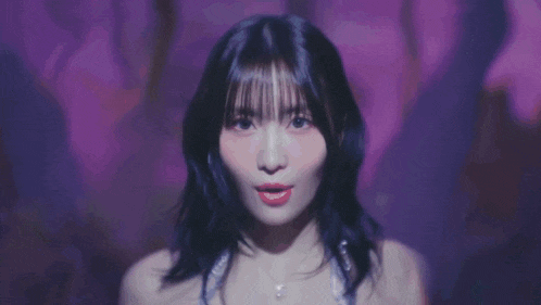 a close up of a woman 's face in a dark room with purple lights .