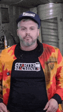 a man wearing a quarter machine t-shirt and a colorful jacket