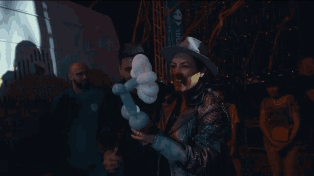 a woman is holding a flower made out of balloons in front of a sign that says premiere