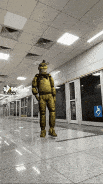 a man in a yellow costume is standing in a hallway with a handicap sign on the wall