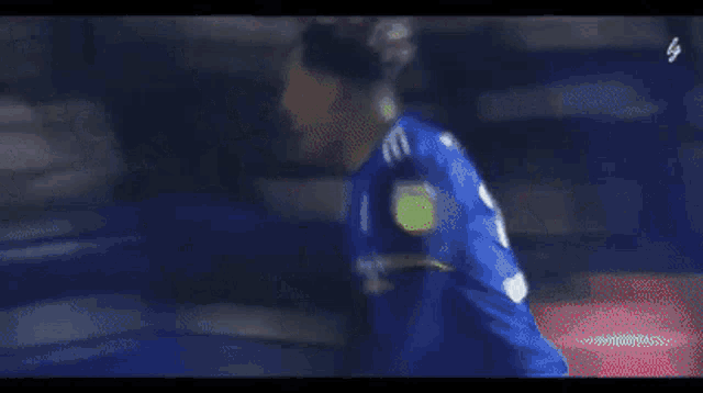 a blurry picture of a soccer player wearing a blue jersey with the number 37 on it