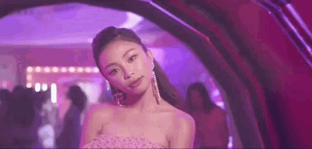 a woman in a pink strapless dress and earrings is standing in a tunnel .