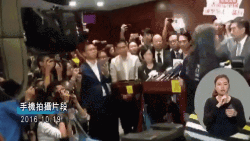 a group of people are standing in front of a sign that says ' hong kong '