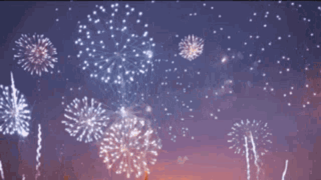 a woman is standing on a rooftop with fireworks going off in the background