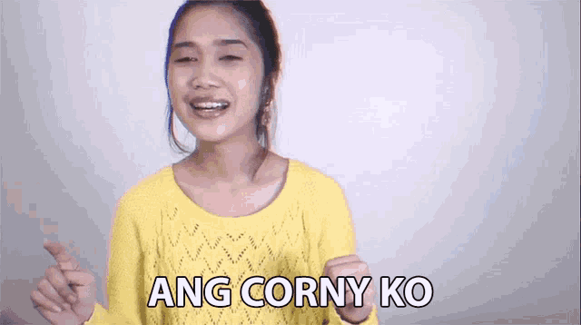 a woman in a yellow sweater is making a funny face and says ang corny ko