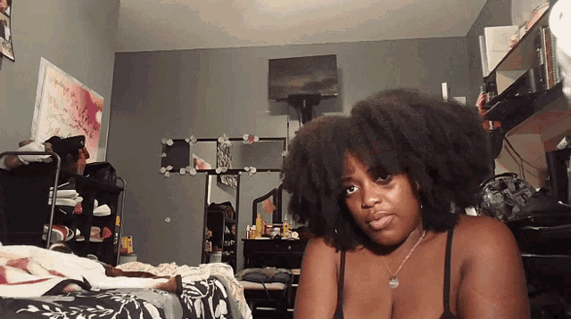 a woman in a black bra is sitting on a bed in a bedroom