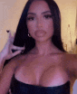 a woman is taking a selfie with her phone while wearing a black strapless dress .