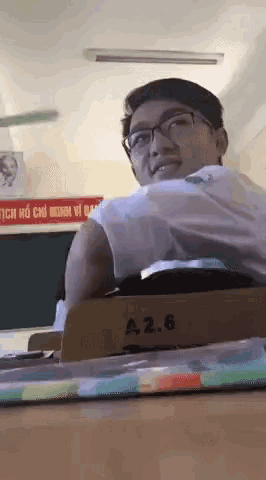 a young man sits at a desk with a 2.6 written on it
