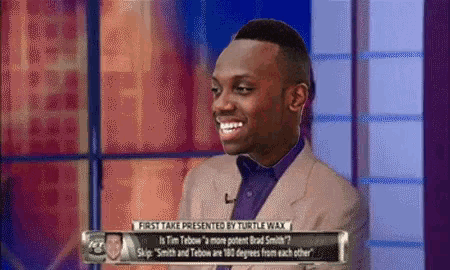 a man in a suit and tie is smiling on a tv show