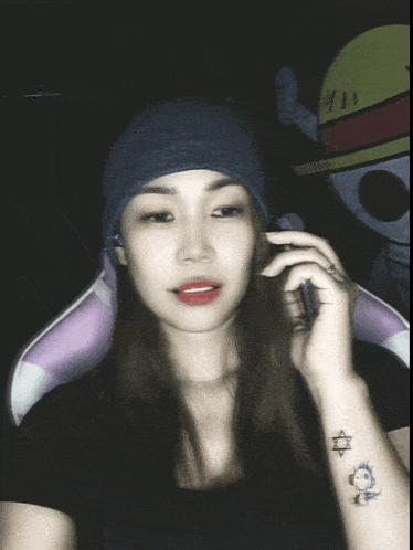 a woman wearing a beanie talks on a cell phone with ano written below her