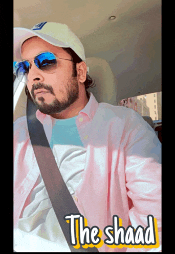 a man wearing sunglasses and a hat is sitting in a car with the shaad written on the side