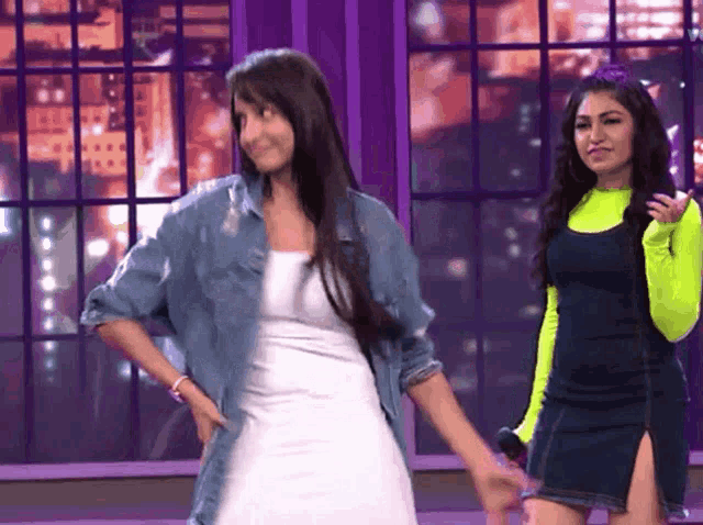 two women are dancing in front of a purple wall