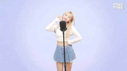 a woman stands in front of a microphone with tong tong written on the bottom right