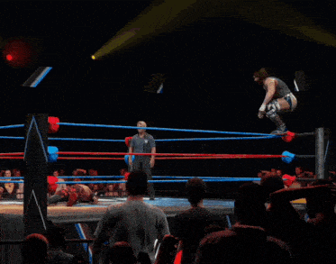 a wrestler jumps in the air while a referee watches from the sidelines