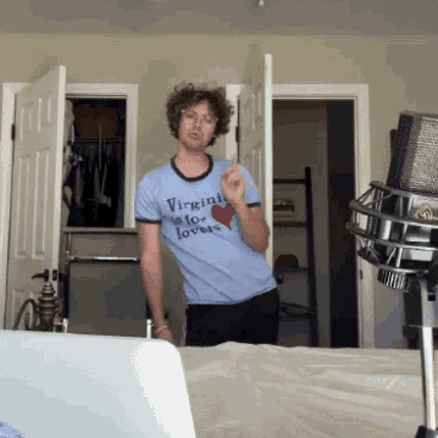 a man wearing a shirt that says virginia loves lovers is standing in front of a microphone
