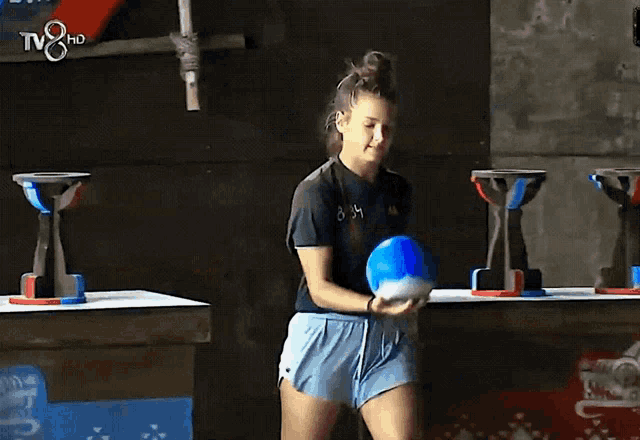 a woman is juggling a ball in front of a tv 8 hd sign