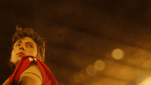 a young man in a red shirt looks up at the sky