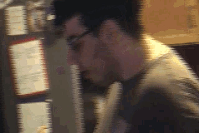 a blurry picture of a man wearing glasses and a shirt that says ' a ' on it
