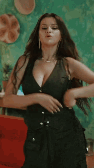 a woman in a black vest is standing in front of a couch