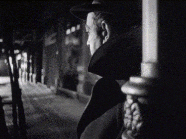 a black and white photo of a man looking out a window