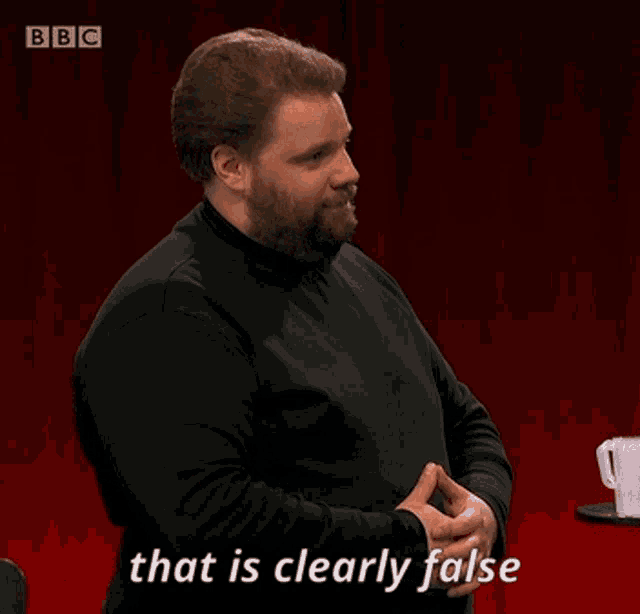 a man is standing in front of a red curtain and saying that is clearly false .