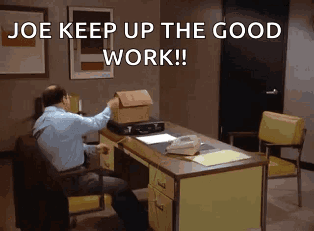 a man is sitting at a desk with a model house on top of it and the words joe keep up the good work .